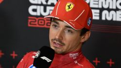 leclerc with a microphone wearing ferrari team kit and cap