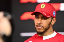 hamilton speaking to reporters wearing his ferrari gear