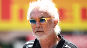 Flavio Briatore wearing his sunglasses and Alpine F1 team wear in front of a Pirelli sign