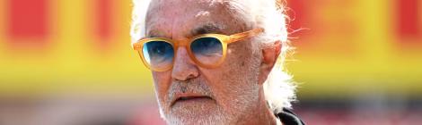 Flavio Briatore wearing his sunglasses and Alpine F1 team wear in front of a Pirelli sign