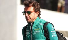 fernando alonso walking with a backback wearing his Aston Martin F1 team wear
